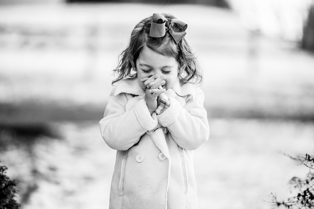 Grijswaarden shot van een schattig meisje dat een wens doet met gesloten ogen