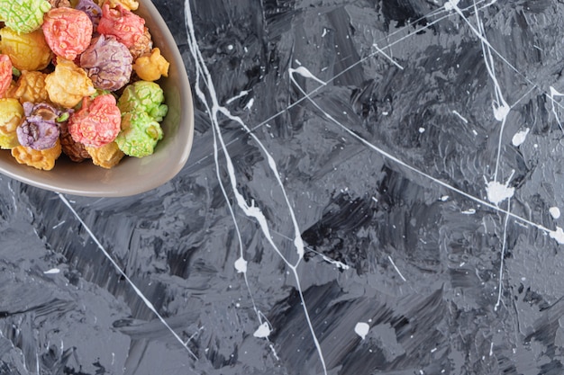 Gratis foto grijze kom met heerlijke kleurrijke popcorns op marmeren tafel.