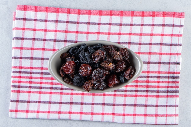 Grijze kom smakelijke gedroogde dadels op gestreept tafelkleed.