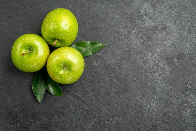 groene appels drie groene appels met bladeren op de donkere tafel