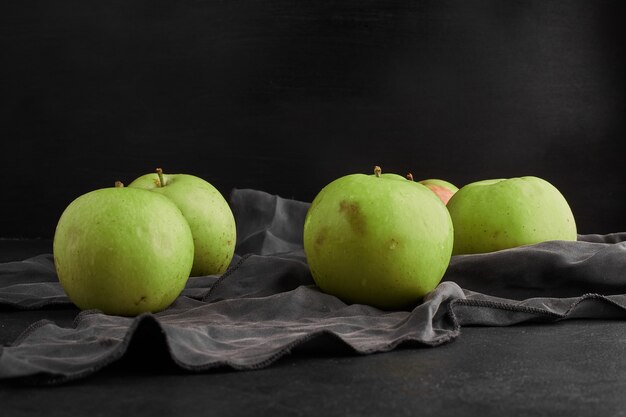 Groene appels geïsoleerd op zwarte achtergrond op grijs tafelkleed.