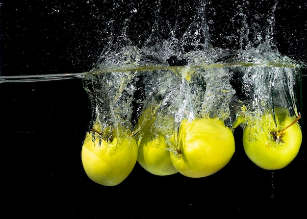 Groene appels spatten in water tegen zwarte achtergrond