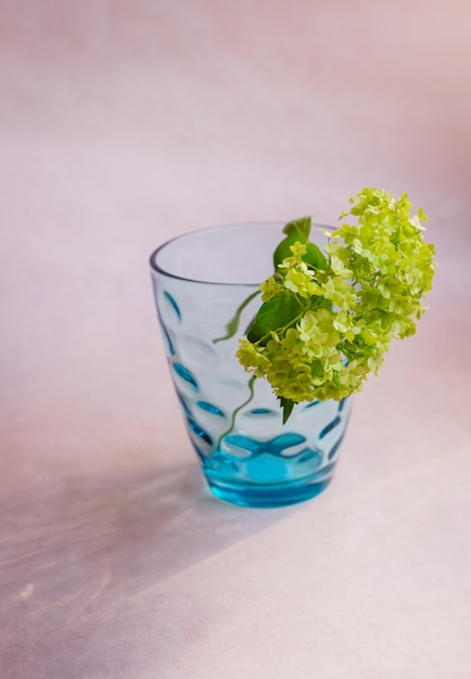Groene bloem staat in blauw glas