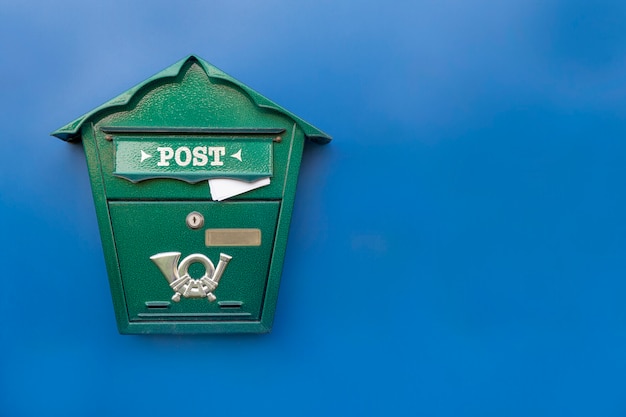Groene brievenbus met binnen plakkende brief op een blauwe achtergrond