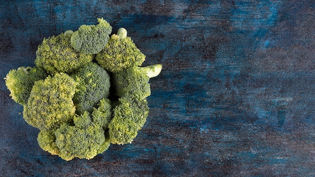 Gratis foto groene broccoli verspreid op blauwe tafel