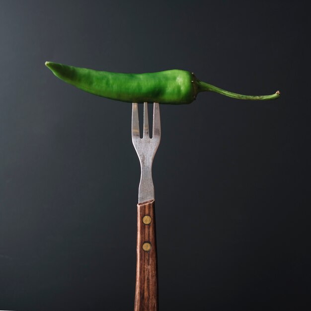 Groene chili peper in vork op zwarte achtergrond
