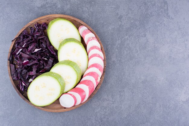 Groene courgetteplakken met gehakte paarse kool in een houten schotel