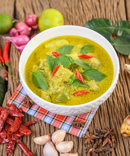 Gratis foto groene curry in een kom met limoen, rode ui, citroengras, knoflook en kaffir limoenblaadjes