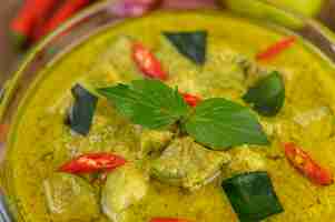 Gratis foto groene curry in een kom op houten tafel.