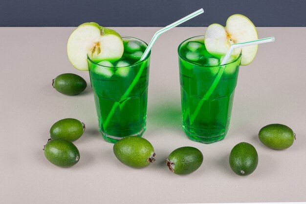 Groene dranken met appel, feijoa en stro op wit