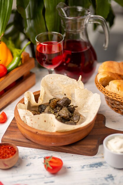 Groene druivenbladeren gevuld met vlees, rijst, kruiden, ui en gekookt in olijfolie, geserveerd met lavash en brood. Yarpag dolmasi, yaprak sarmasi