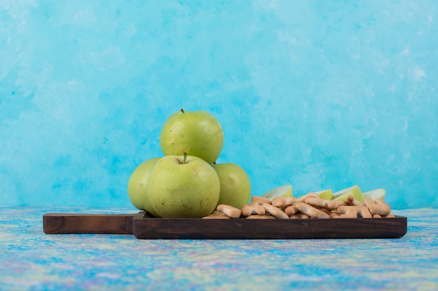 Groene gesneden appels met crackers op het houten bord op blauw.