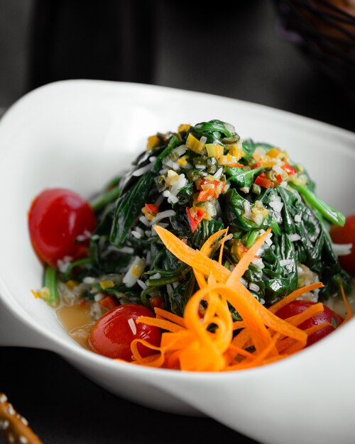 Groene groentesalade met gehakte wortel en tomaten.