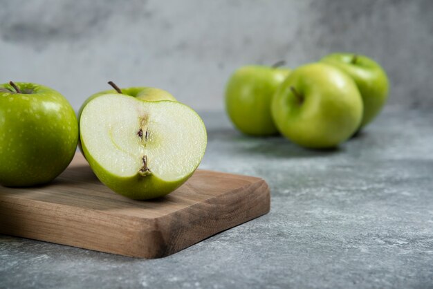 Groene hele en gesneden appels op een houten bord.