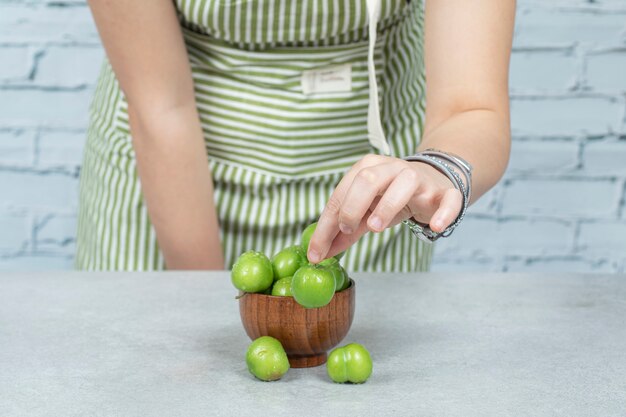 Groene kersen pruimen aanbrengend een houten kom