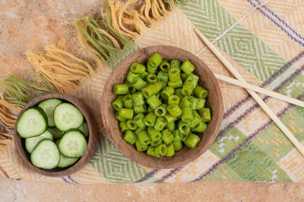 Groene penne pasta met plakjes komkommer op tafellaken.