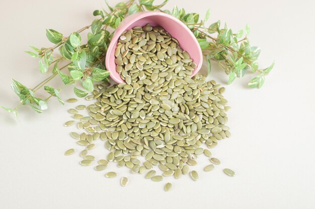 Groene pompoenpitten in een container op beton.