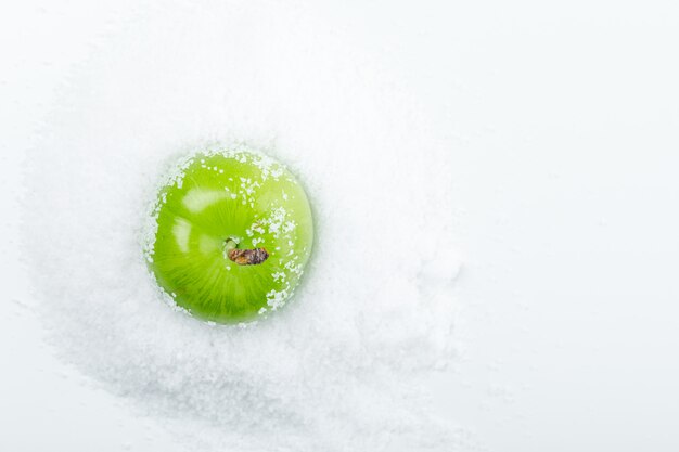 Groene pruim met zoutkristallen bovenaanzicht op een witte muur