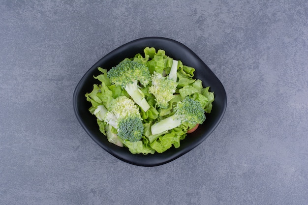 Groene salade in een bord op blauwe ondergrond