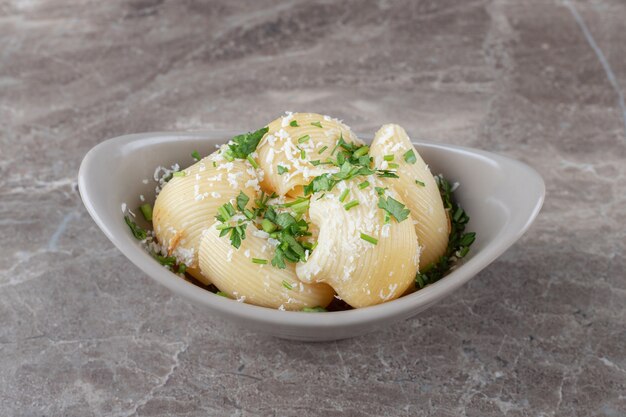 Groenen en pittige pasta in kom, op de marmeren achtergrond.