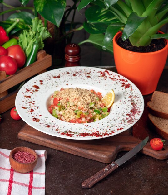 Groente, tomaten, komkommersalade met crackers. salade met sumakh en citroen op de keukentafel in witte plaat