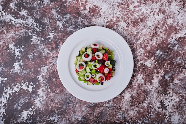 Groentesalade met gehakte en gehakte ingrediënten gemengd met olie, bovenaanzicht.