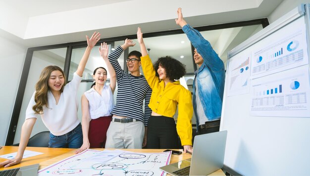 Groep aziatische jonge creatieve gelukkige mensen-ondernemers op de achtergrond van een zakelijke bijeenkomst. Goed leiderschap en teamwork leiden tot succes