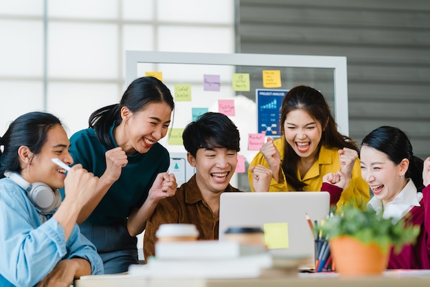 Groep aziatische jonge creatieve mensen in slimme vrijetijdskleding die zaken bespreken vieren het geven van vijf na het omgaan met een gelukkig gevoel en het ondertekenen van een contract of overeenkomst op kantoor. collega teamwerk concept.