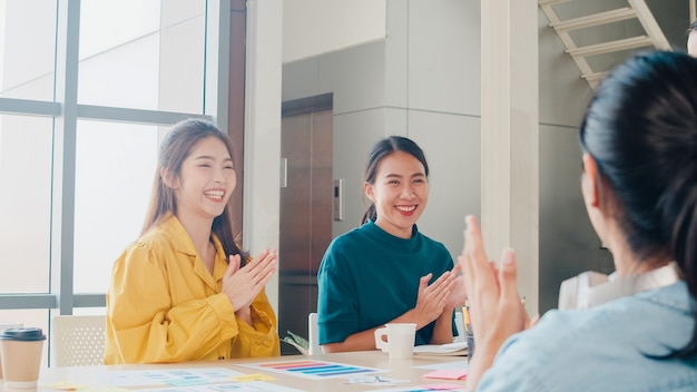 Groep aziatische jonge creatieve mensen in slimme vrijetijdskleding die zaken bespreken vieren het geven van vijf na het omgaan met een gelukkig gevoel en het ondertekenen van een contract of overeenkomst op kantoor. collega teamwerk concept.