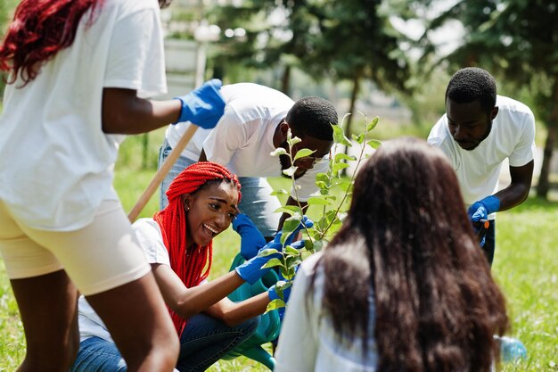 Groep gelukkige afrikaanse vrijwilligers die boom planten in park Afrika vrijwilligerswerk voor liefdadigheidsmensen en ecologieconcept