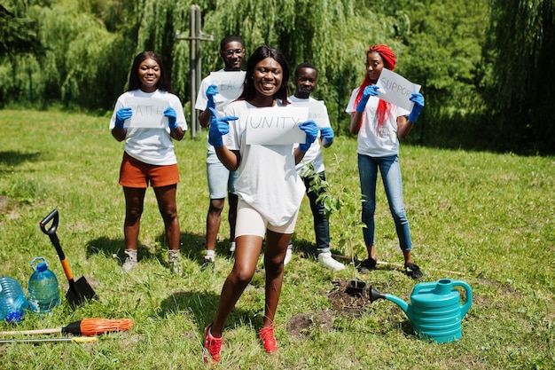 Groep gelukkige afrikaanse vrijwilligers houdt een leeg bord vast met eenheidsteken in park Afrika vrijwilligerswerk voor liefdadigheidsmensen en ecologieconcept