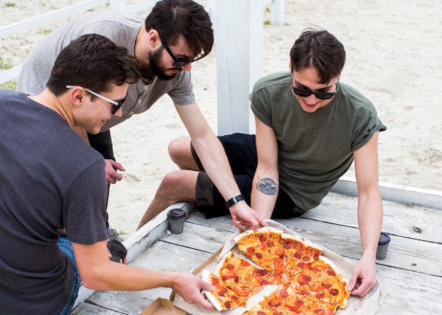 Gratis foto groep gelukkige mensen met pizza op rust