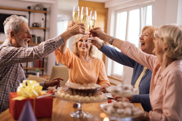 Groep gelukkige volwassen mensen die plezier hebben tijdens het roosteren met champagne op verjaardagsfeestje