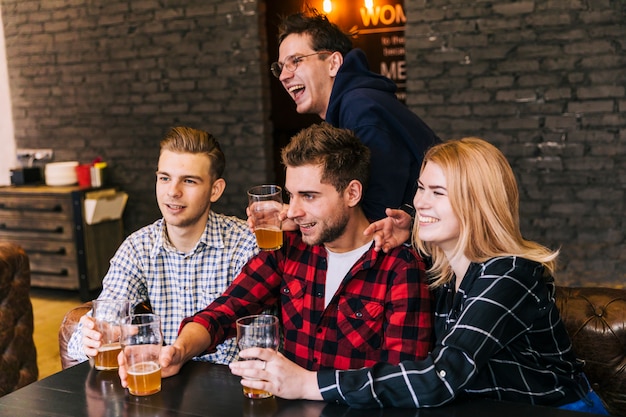 Groep gelukkige vrienden die samen van het bier in het restaurant zitten genieten
