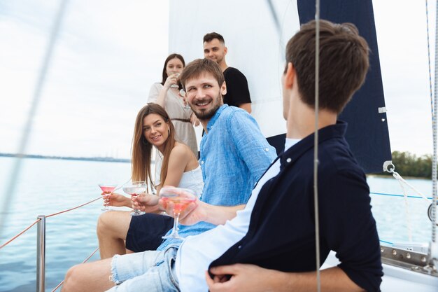 Groep gelukkige vrienden die wodkacocktails drinken op bootfeest buiten, zomer,