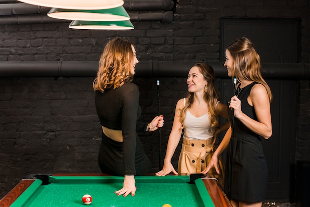 Groep gelukkige vrouwelijke vrienden die zich dichtbij snookerlijst bevinden