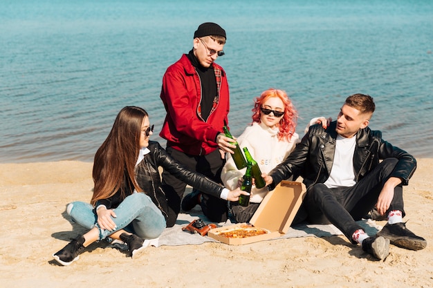 Groep glimlachende vrienden op picknick bij strand
