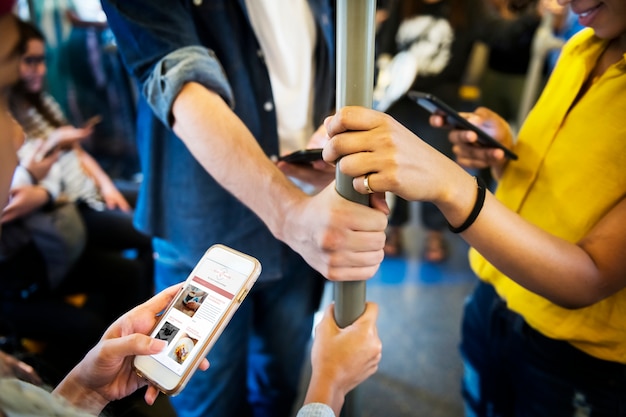 Groep jonge volwassen vrienden die smartphones in de metro gebruiken