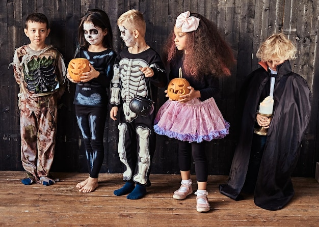 Groep kinderen in kostuums tijdens halloween-feest in een oud huis. halloween-concept.