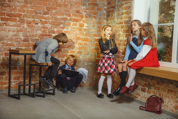 Groep kinderen tijd samen doorbrengen na school. Knappe vrienden rusten na de lessen voordat ze huiswerk gaan doen. Modern loft interieur. Schooltijd, vriendschap, onderwijs, saamhorigheidsconcept.