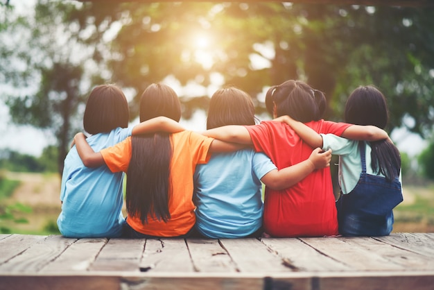 Gratis foto groep kinderen vrienden arm rond elkaar zitten