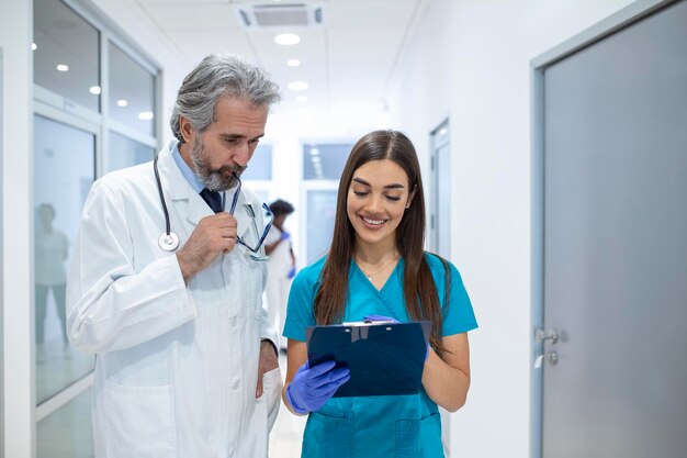 Groep medici met klembord bespreken langs ziekenhuisgang Arts en verpleegkundige briefing medisch rapport