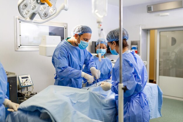 Groep medisch team die dringend een chirurgische ingreep uitvoert en de patiënt helpt in het theater in het ziekenhuis Medisch team dat een chirurgische ingreep uitvoert in een lichte moderne operatiekamer