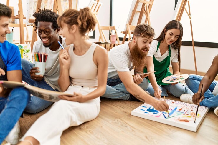 Groep mensen glimlachend blij tekening zittend op de vloer in kunststudio