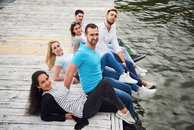 Groep mooie jonge mensen op de pier, de tevredenheid van vrienden creëert een emotioneel leven.