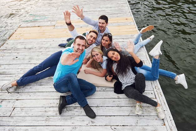 Groep mooie jonge mensen op de pier, de tevredenheid van vrienden creëert een emotioneel leven.