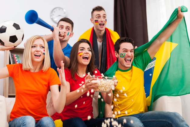 Groep multinationale mensen juichen voetbalwedstrijd thuis