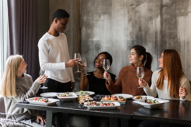 Gratis foto groep positieve jongeren die bij diner roosteren