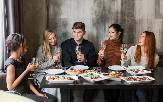 Gratis foto groep positieve jongeren die van diner en wijn genieten