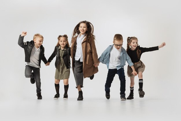 Groep stijlvolle kinderen lopen springen poseren geïsoleerd over grijze studio achtergrond Retro fashion style